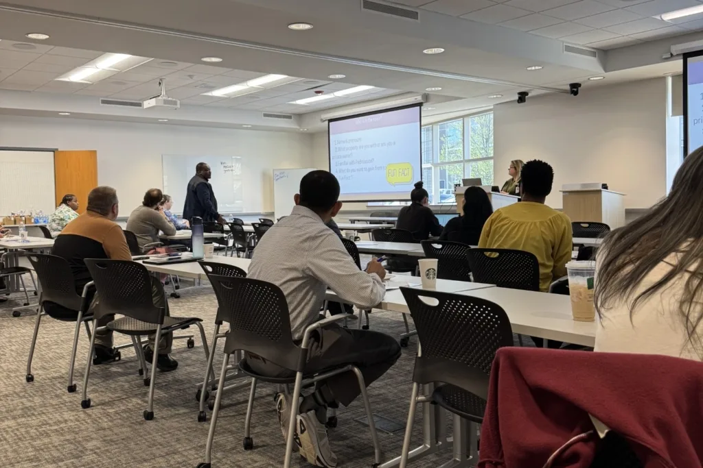A HomeNow Indy session in Indianapolis, with attendees following a presentation on a projected screen.
