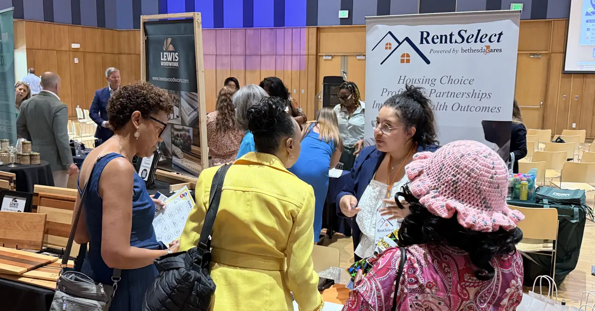 RentSelect staff talking with attendees at a community event in Montgomery County, Maryland, beside the program’s banner.