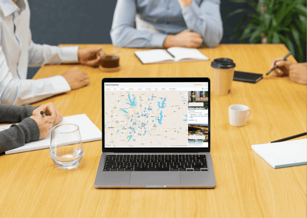 laptop3 Laptop screen showing a housing search map with both available units and reserved units displayed, as staff review shared housing inventory together during a meeting.